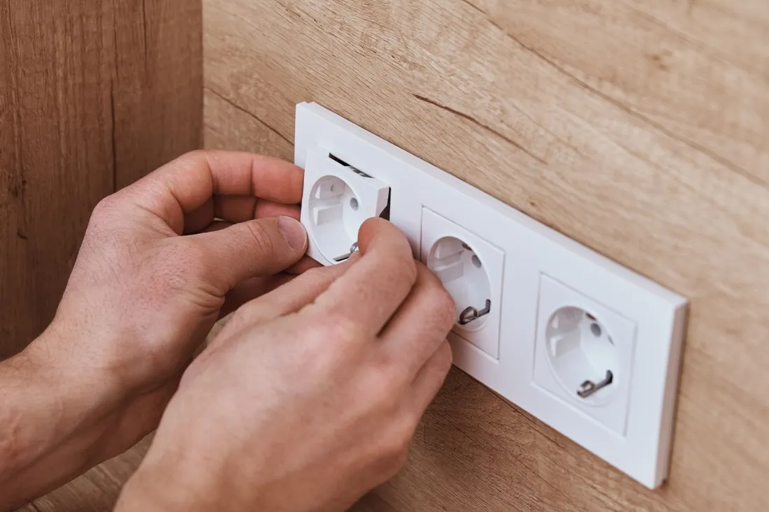 Zakładanie potrójnej białej ramki gniazd elektrycznych na ścianie wykończonej drewnem