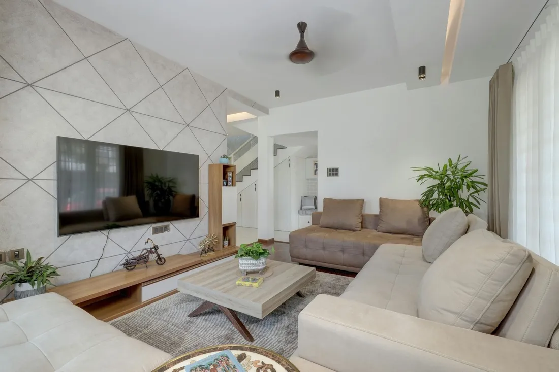 Salon z jasną ścianą o geometrycznym wzorze z telewizorem i dwiema jasnymi sofami
